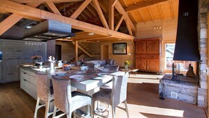 Un'ampia cucina con isola centrale, travi in legno e camino in pietra.