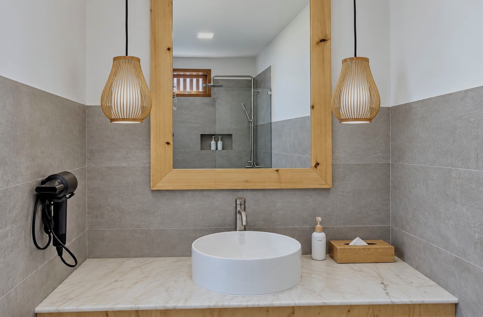 A modern bathroom with a round sink, wooden vanity, and a large mirror.