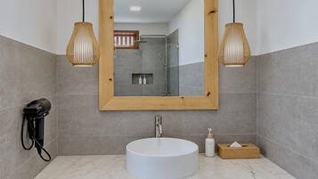 A modern bathroom with a round sink, wooden vanity, and a large mirror.