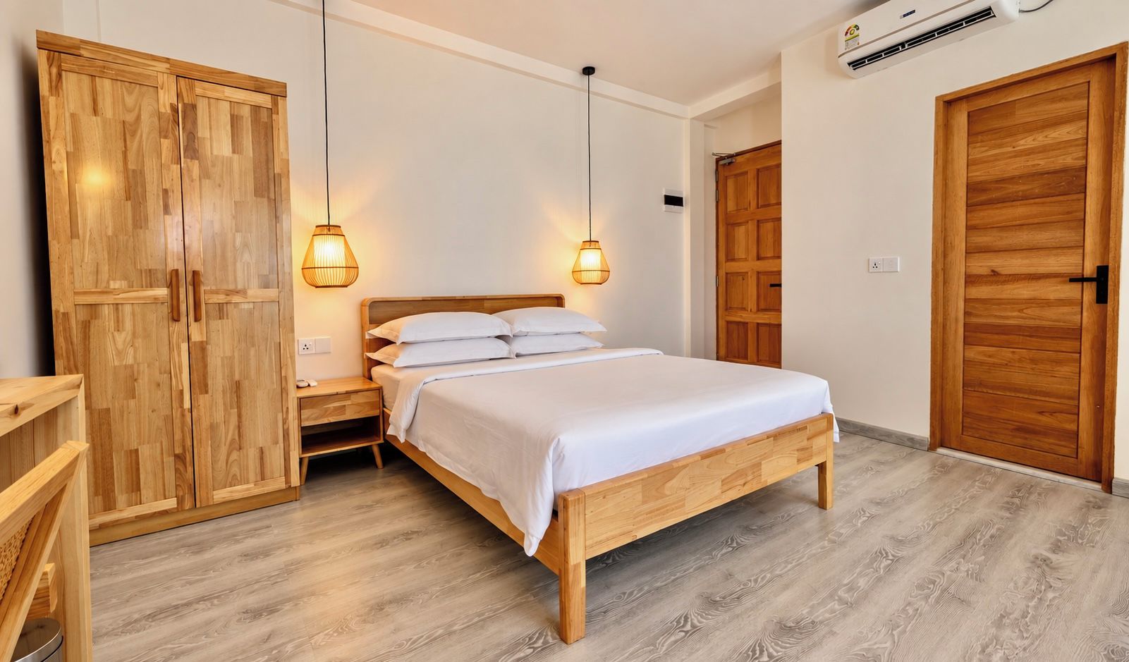 A bedroom with a wooden bed, two bedside tables, a wardrobe, and two pendant lights.