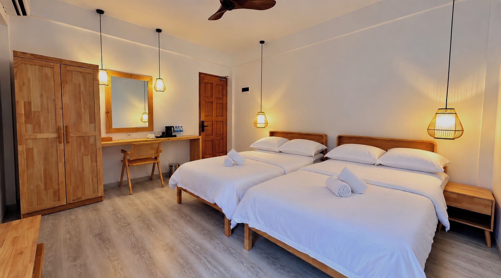 Een hotelkamer met twee bedden, een bureau en een kledingkast.