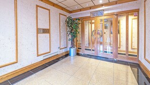Eine Hotellobby mit Fliesenboden, Holzvertäfelung, einem Topfpflanzen und einem Glastür-Eingang.