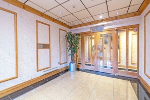 A hotel lobby with a tiled floor, wooden paneling, a potted plant, and a glass door entrance. - Foregate Apartment by Guestz (Chester)