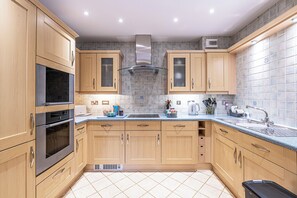 A modern kitchen with wooden cabinets, a stainless steel range hood, and a tiled backsplash. - Foregate Apartment by Guestz (Chester)
