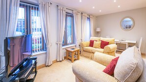 Ein Wohnzimmer mit einer Couch, einem kleinen Tisch und einem Fernseher.