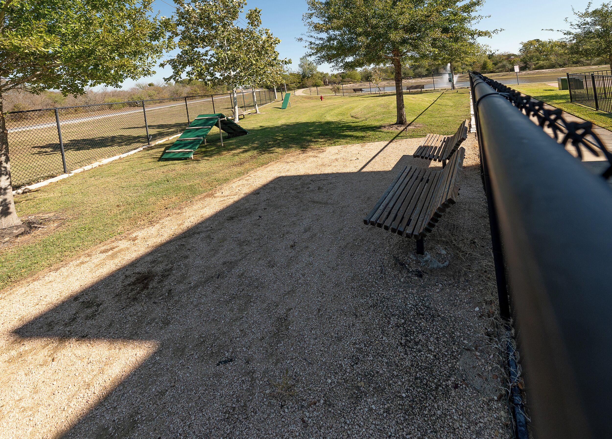A gravel area with benches and a fence.