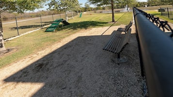 A gravel area with benches and a fence.