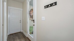A hallway with a white door, a glass door leading outside, and a wall-mounted sign with Arabic script. - "Pooling Around " in Aggieland" (College Station)