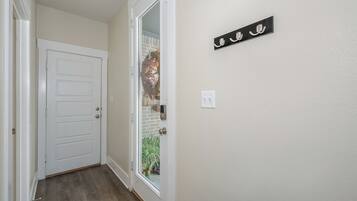 A hallway with a white door, a glass door leading outside, and a wall-mounted sign with Arabic script.