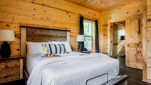 Une chambre dans une cabane en bois, avec un lit, des tables de chevet et une fenêtre.