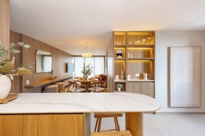 Eine moderne Küche mit Marmorarbeitsplatte, Holzschränken und einem Essbereich mit rundem Tisch und Stühlen.