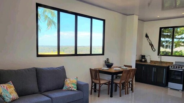 Un espace de vie moderne comprenant un canapé, une table à manger, des chaises et une cuisine équipée d’une cuisinière et d’un évier.