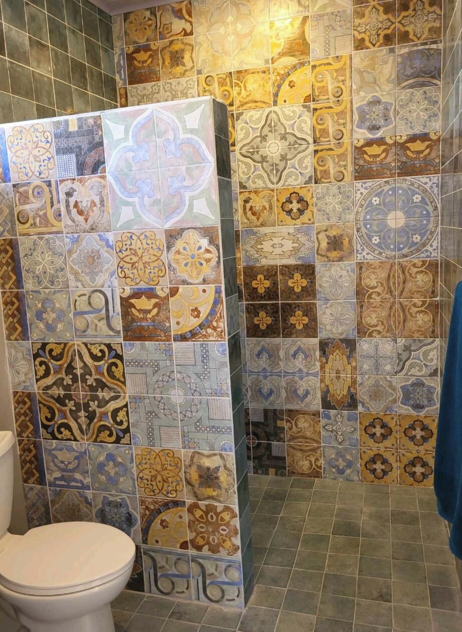 Un baño con una variedad de azulejos estampados en paredes y suelo.