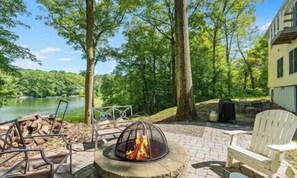 A patio with a fire pit, outdoor seating, and a view of a lake. - Private LAKE FRONT Cozy 3-bedroom house in charming Vernon Township with AC (Vernon Township)