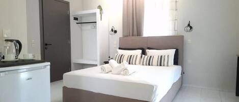 Una habitación de hotel con cama, escritorio con tetera y armario.