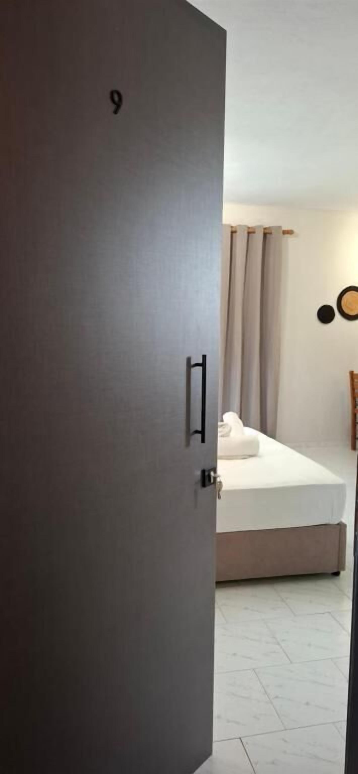 A hotel room with a bed, a door with a number, and a curtain.