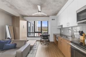 A modern kitchen with a large window, a dining area with a sofa and chair, and a ceiling fan. - Cozy Murphy Hideaway Studio 87 (Birmingham)