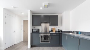 Una cucina moderna con mobili grigi, un frigorifero in acciaio inossidabile e un forno integrato.