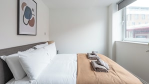 Una camera d'albergo con un letto, cuscini, una coperta e un quadro appeso al muro.