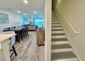 A modern interior with a staircase, a dining area with a table and chairs, and a view of the outdoors. - Blue Heron: Kayaks, Bay Views & more! (Escambia County)