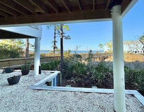 An outdoor covered area with a view of the beach, wooden benches, and potted plants. - Bay View 108: Great Views, Pool & More! (Escambia County)