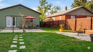 Une maison verte avec un patio, un parasol rouge et une clôture en bois.