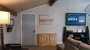 Un salon avec un téléviseur, un meuble, une porte et un tableau encadré au mur.
