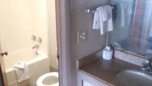 A bathroom with a toilet, a bathtub, a sink, and a mirror. - Hometown inn (Flint)
