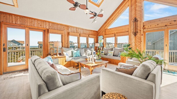 A spacious living room with a large window, a ceiling fan, and a wooden interior.