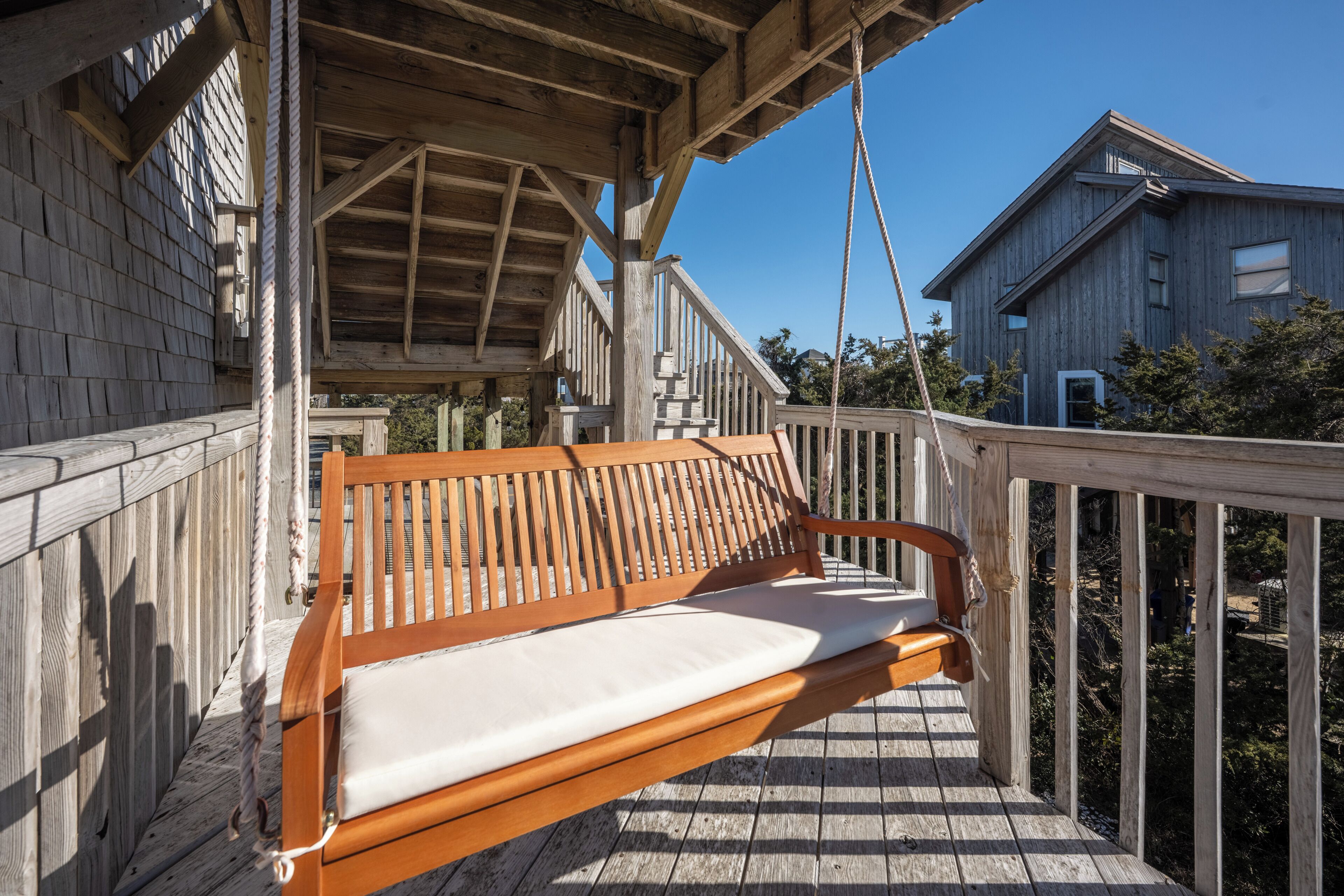 A wooden deck with a wooden bench and a railing.