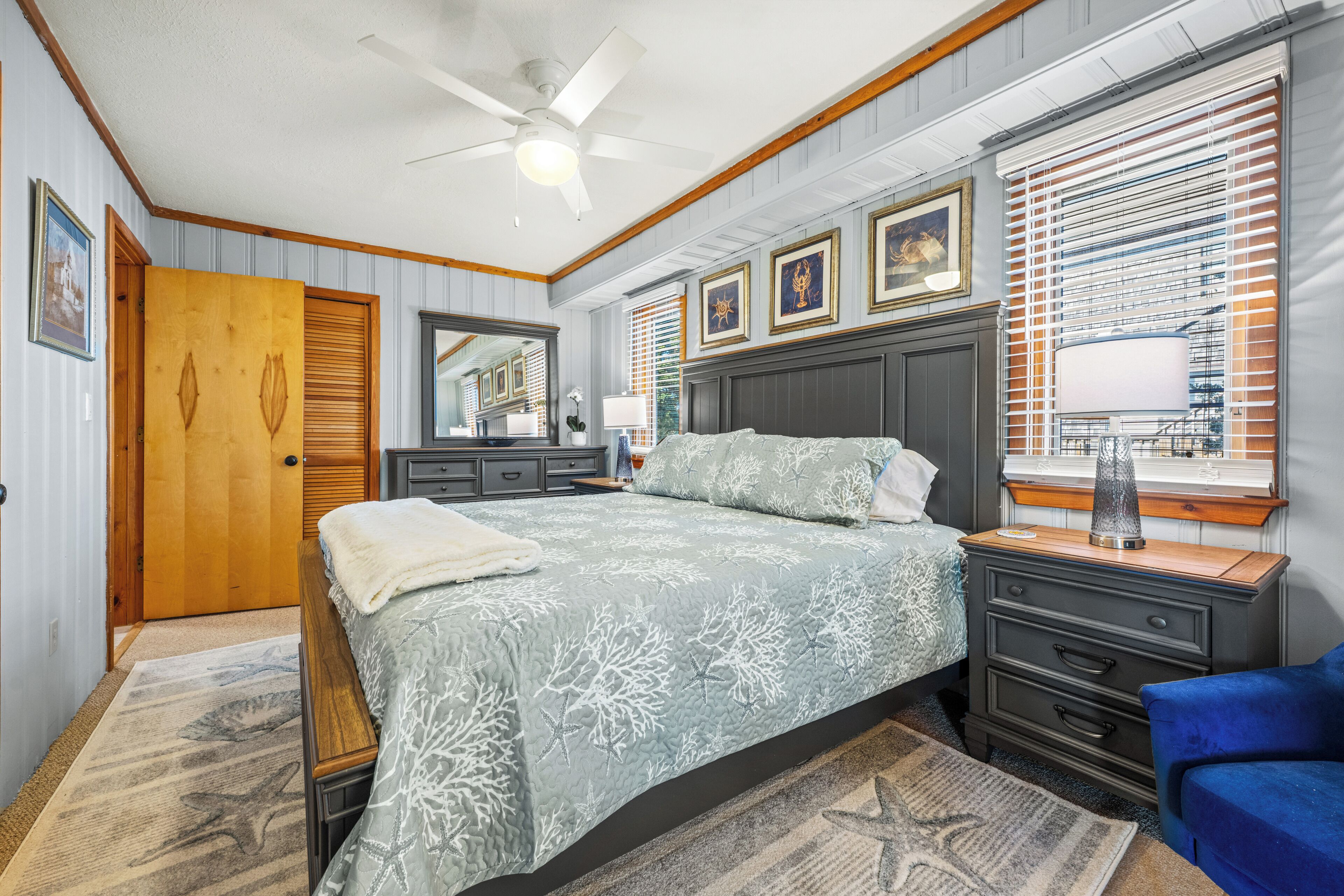 A bedroom with a bed, dresser, nightstand, and a ceiling fan.