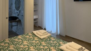 Ein Schlafzimmer mit Bett, Fernseher, Badezimmer mit Waschbecken und Schrank.
