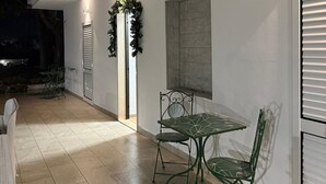 Eine Terrasse mit Tisch und Stühlen, einem Zierkranz und einem an der Wand befestigten Kunstwerk.