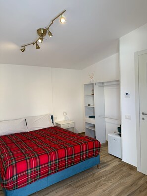 A bedroom with a bed, bedside table, lamp, wardrobe, and a ceiling light fixture. - Aura Garden Rooms (Campania)