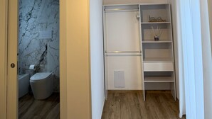 Ein Schlafzimmer mit Holzboden, einem Bett, einem Kleiderschrank und einem Badezimmer mit Marmorwand.