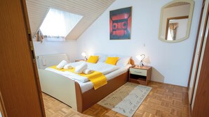 Ein Schlafzimmer mit Bett, Nachttischen, einem Fenster, einer Heizung und einem Spiegel.