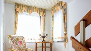 Ein Zimmer mit Holzstuhl, Tisch und einem Vorhangfenster.