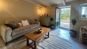 Een woonkamer met een bank, een bijzettafeltje, een kast en een potplant.