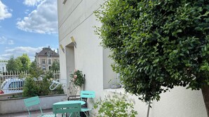 Una terraza con dos macetas grandes de terracota, una silla verde, una mesa y una planta en maceta.