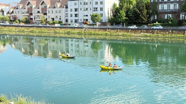 Un río tranquilo con barcos, una hilera de casas y un cielo despejado.