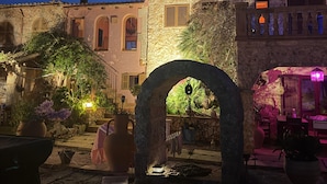 A stone building with an archway, potted plants, and outdoor seating. - Villa can Juanito- Paradise location, very close to the harbor, Porto Cristo beach (Porto Cristo)