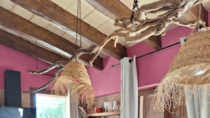 Une cuisine équipée d’une cuisinière, d’un four et d’un lave-vaisselle, avec des poutres en bois au plafond et une fenêtre agrémentée de rideaux.