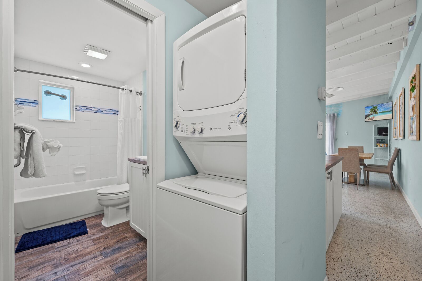 A compact bathroom with a toilet, shower, and a stacked washer and dryer.