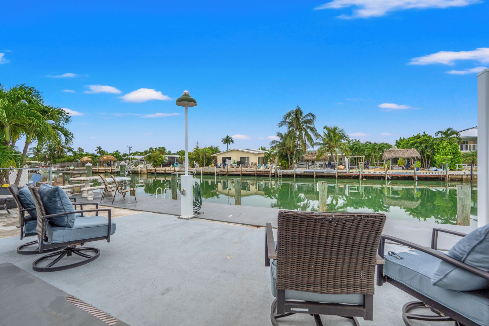 A poolside area with lounge chairs, a lamp post, and a view of the water and surrounding buildings.