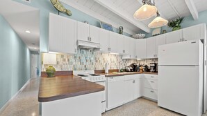 A modern kitchen with white cabinetry, a wooden countertop, a stove, a dishwasher, and a refrigerator. - Beautiful 2-bedroom house with Dock in Key Colony Beach (Key Colony Beach)