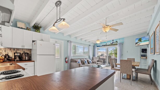 A modern kitchen with white cabinets, a wooden island, and a dining area with chairs and a table. - Beautiful 2-bedroom house with Dock in Key Colony Beach (Key Colony Beach)