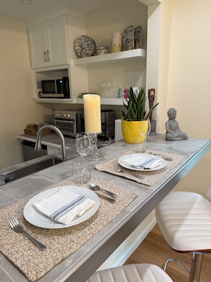 Een moderne keuken met een centraal eiland, witte kasten en een Boeddha-beeld.