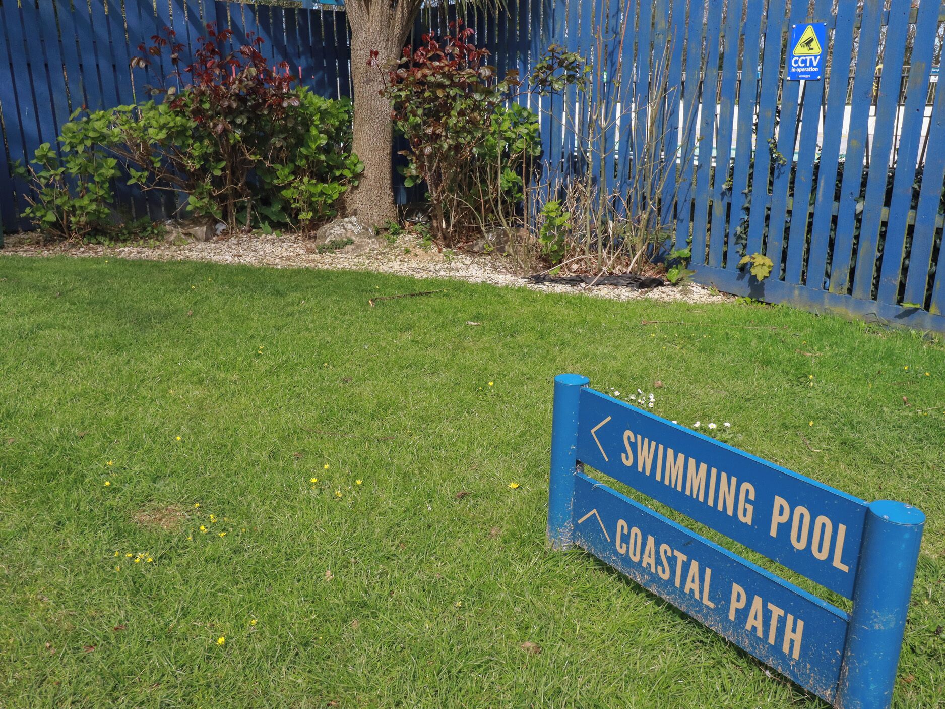 A sign for a swimming pool and coastal path.