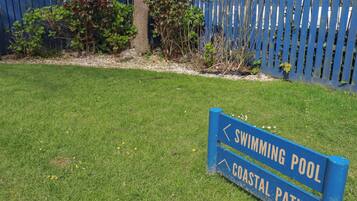 A sign for a swimming pool and coastal path.