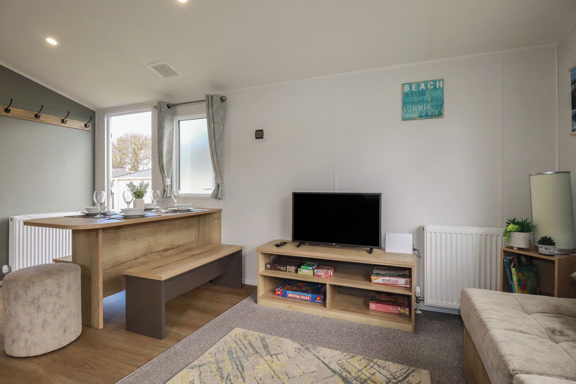 A living room with a TV, bookshelf, and a window with curtains.